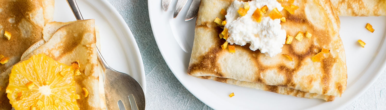 Crepes with orange and cream on brunch plates